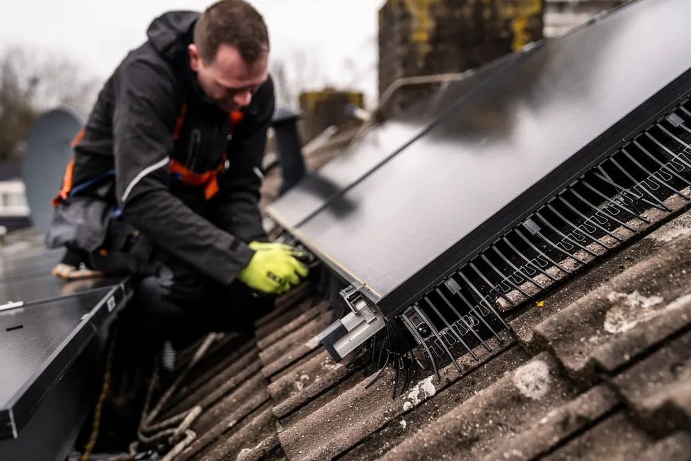 Technician installing BirdBlocker on residential solar panels