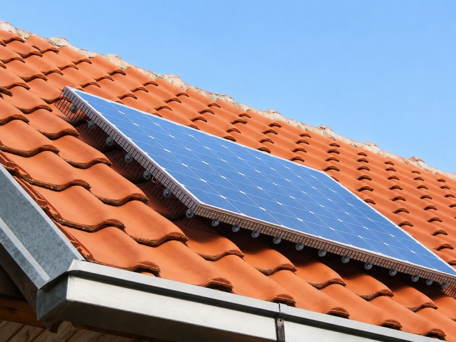 Anti-pigeon mesh installed around solar panels on a red tiled roof